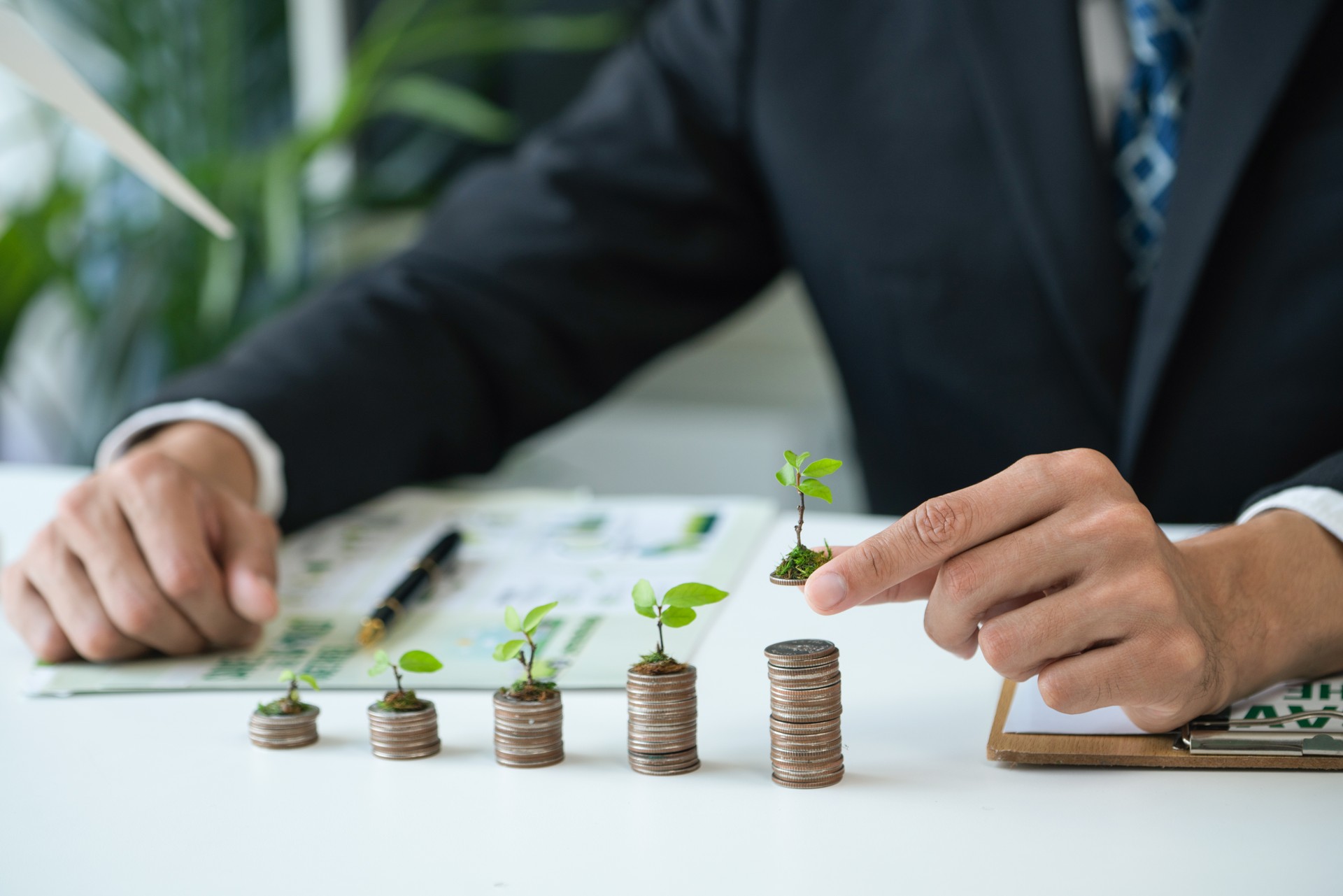 Businessman with coin stack at his office as sustainable money growth. Gyre